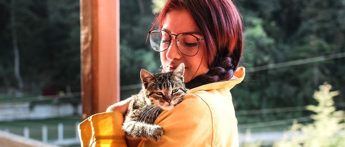 a woman in glasses holding a tabby kitten